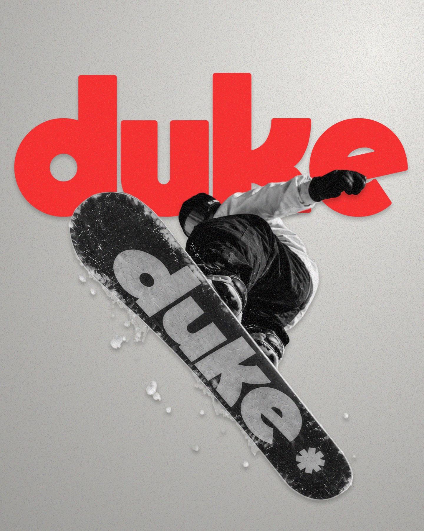 Snowboarder sujetando una tabla roja de Duke en un bosque nevado